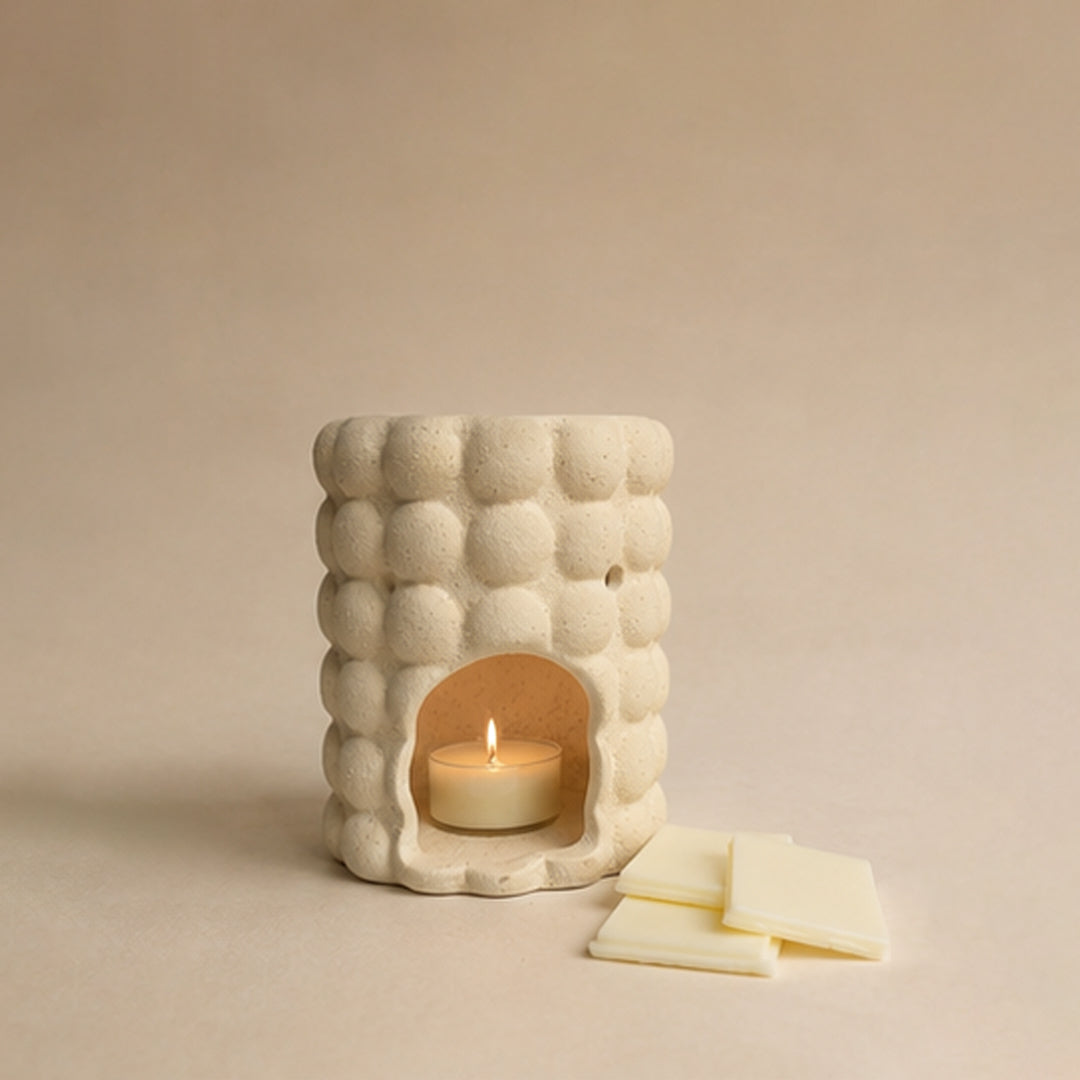 Ceramic burner with a tealight inside on a beige background. Wax melts on the side.
