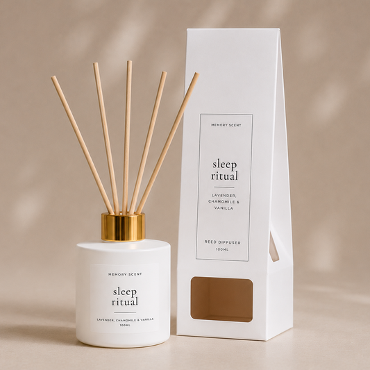 Reed diffuser with gold cap and white jar next to its packaging on a beige background