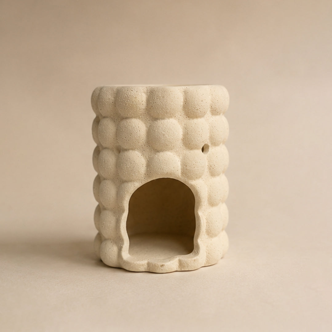 Ceramic bubble wax burner with textured surface on a beige background