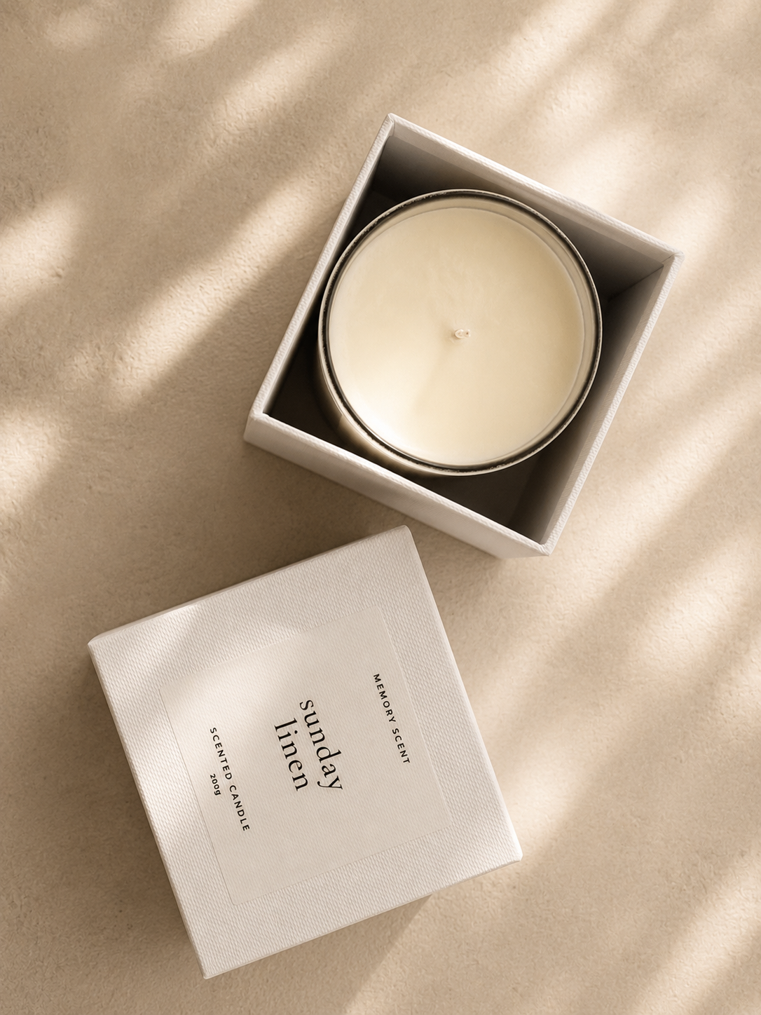 Candle in a box labeled 'Sunday Linen' on a beige surface