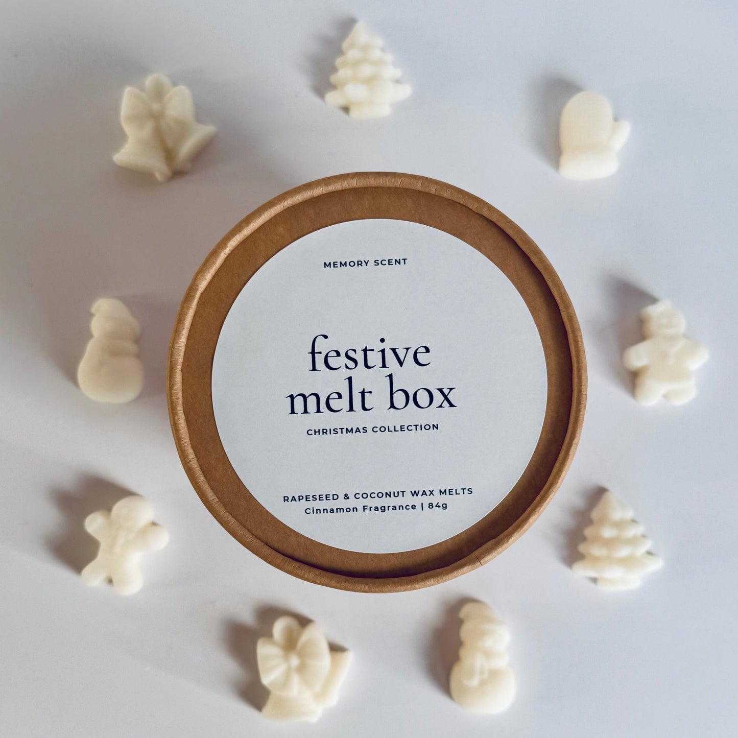 An image showing the Festive melt box with the lid on and label showing, and surrounding the box in a circle are the wax melt shapes that you'd find inside the box.