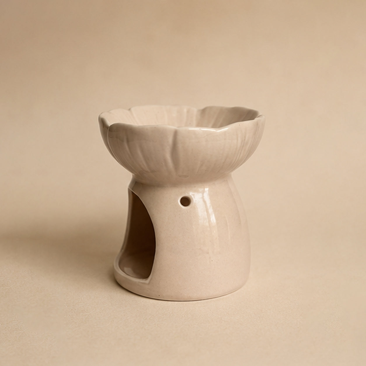Pink blossom ceramic wax burner side view on a beige plain background.