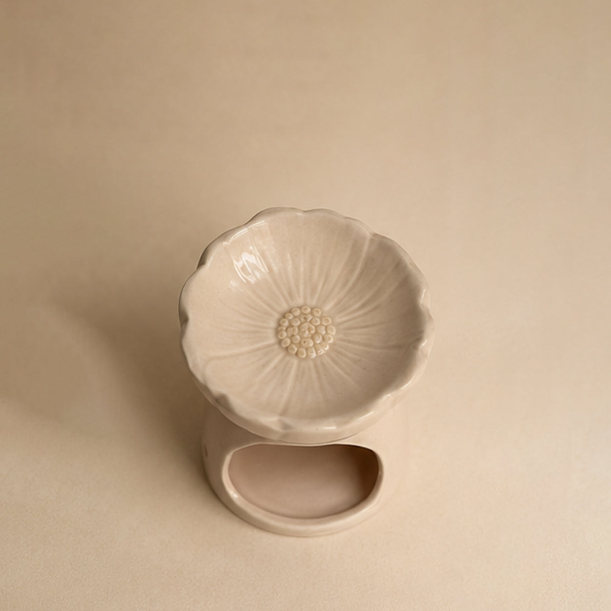 Empty Pink blossom ceramic wax burner top down view on a beige plain background.
