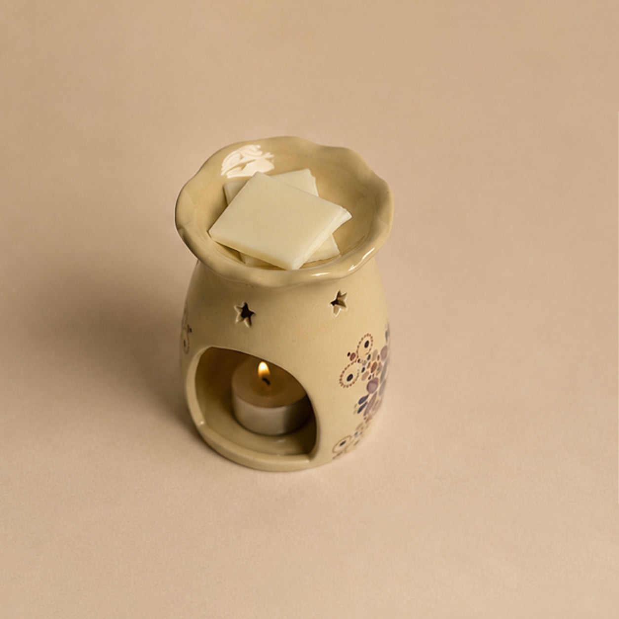 Ceramic wax warmer with a candle inside on a beige background
