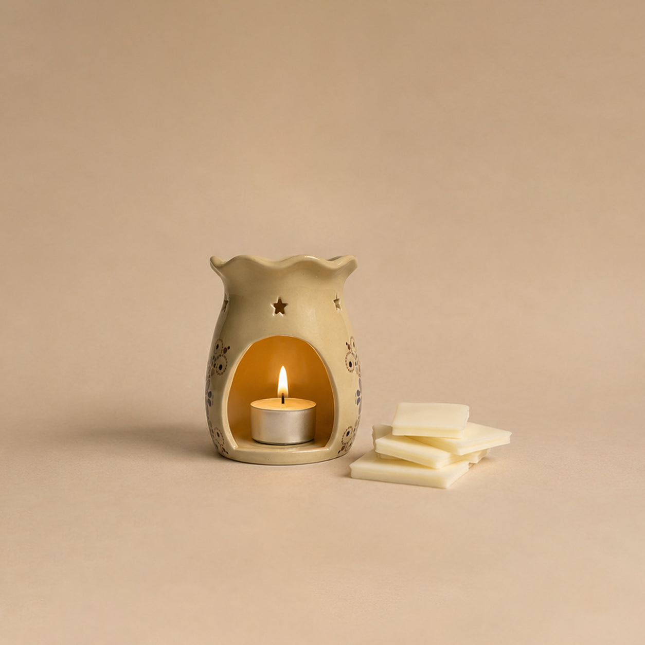 Ceramic wax warmer with a lit candle and wax bars on a beige background