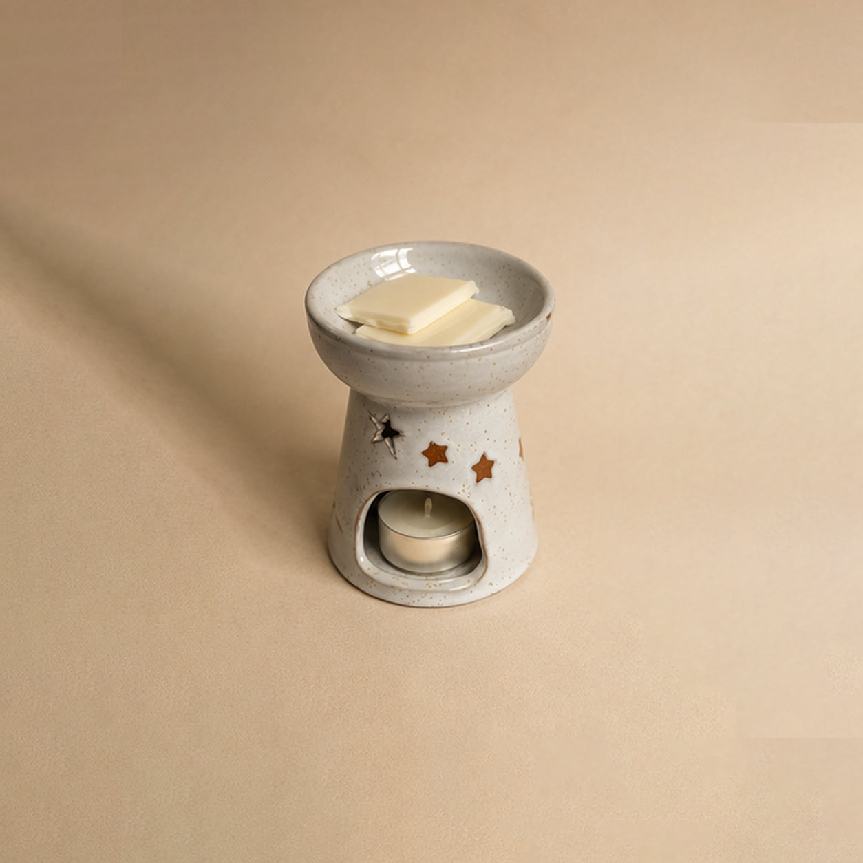 Ceramic wax burner with two wax melt blocks on a beige background