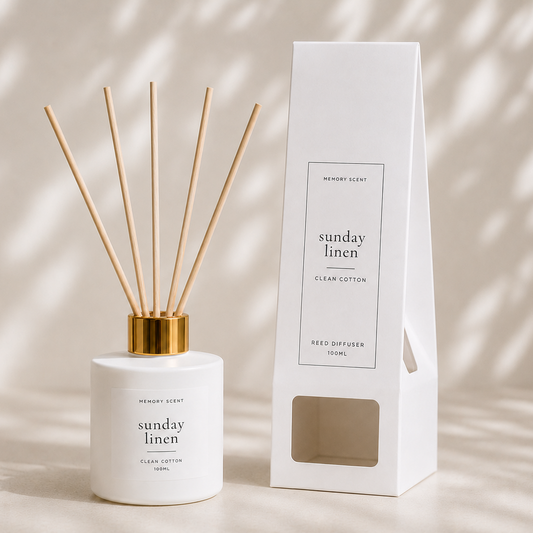 Reed diffuser with gold cap and white container next to its packaging on a neutral background