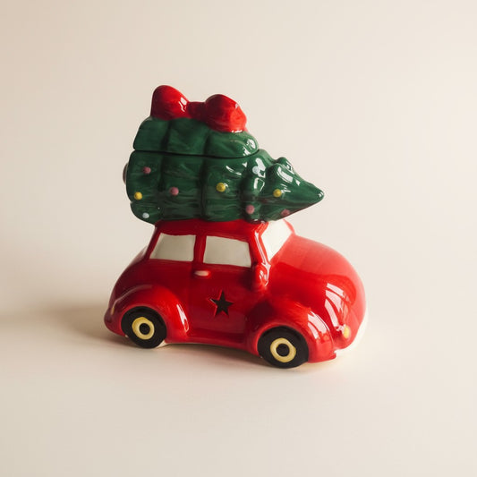 Red wax burner car with a Christmas tree on top against a beige background