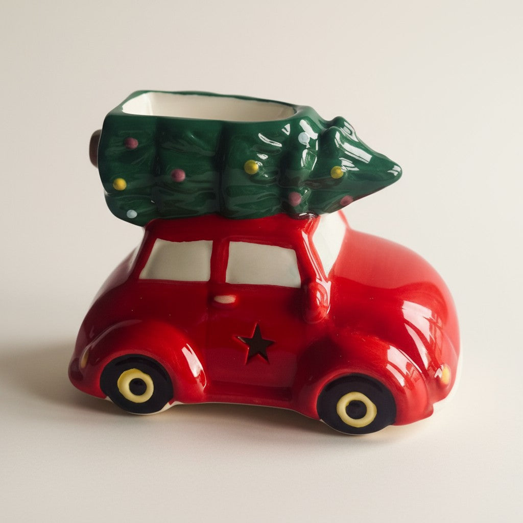 Red car-shaped ceramic wax burner with a green tree on top against a plain background
