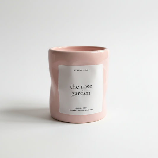 Pink candle labeled 'the rose garden' on a white background